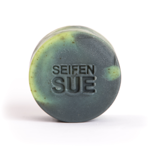 Runde Seife mit Brennnessel und Salbe, schwarz und Grün, Gusstechnik, zylindrische Form, Haarseife, SeifenSUE Logo in die Mitte gestempelt, von vorne